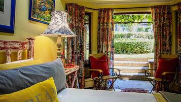 Una habitación con cama, una silla, una mesa y un ventanal con cortinas.