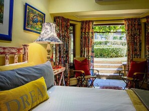 Una habitación con cama, una silla, una mesa y un ventanal con cortinas.