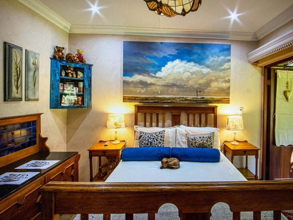Una camera da letto con un letto, due comodini, una panca da notte, un armadio blu e un quadro grande appeso al muro.