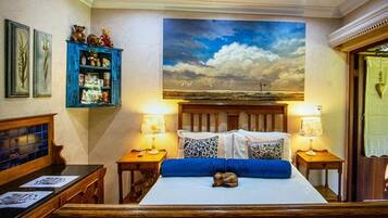 Una camera da letto con un letto, due comodini, una panca da notte, un armadio blu e un quadro grande appeso al muro.
