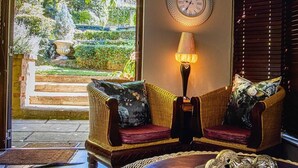 A room with wicker furniture, a wall clock, and a decorative lamp.
