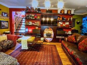A cozy living room with a fireplace, a television, and a staircase leading to an upper level.
