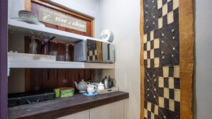 A kitchen with a coffee station sign, shelves with kitchenware, and a patterned wall.