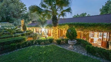 A well-maintained garden with a pathway leading to a building with a tiled roof.