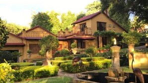A house with a garden, a fountain, and a bird statue.
