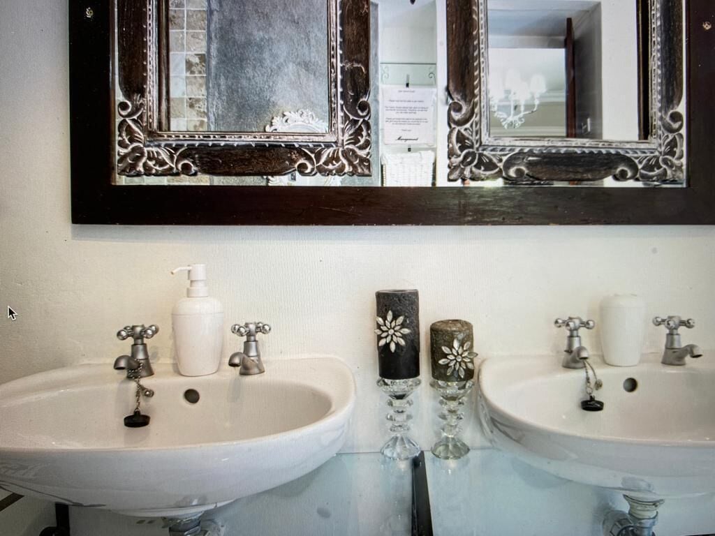 A bathroom with two sinks, a mirror, and a decorative wall.