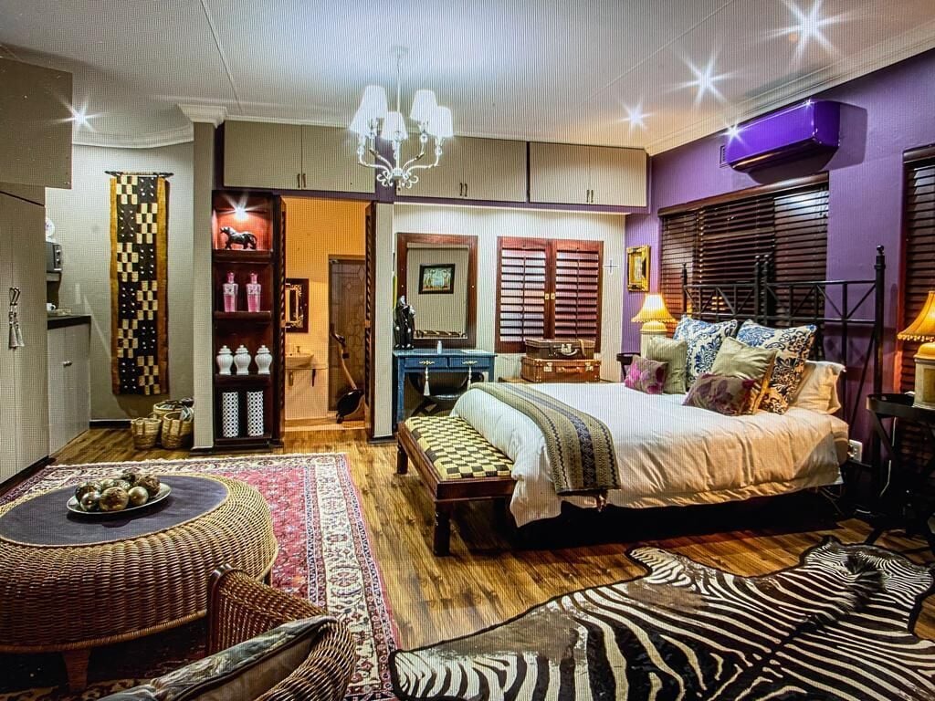 A bedroom with a bed, bedside table, lamp, and a large rug.