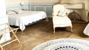 Quarto com cama, poltrona, piso de madeira, tapete estampado e lareira.