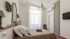 A bedroom with a bed, a mirror, a chandelier, a television, and a wardrobe. - Etienne Suite (Napoli)