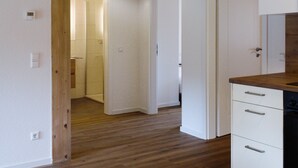 Ein Flur mit Holzboden, weißen Wänden und einer Küchenzeile mit weißen Schränken und einer Holz Arbeitsplatte.