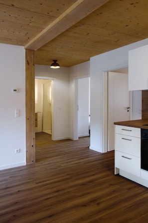 Ein Flur mit Holzboden, weißen Wänden und einer Küchenzeile mit weißen Schränken und einer Holz Arbeitsplatte.