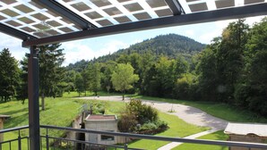 Ein Balkon mit Blick auf eine grüne Landschaft, einen Weg und ein kleines Gebäude.