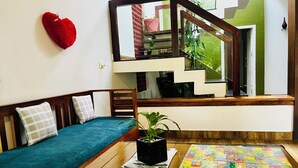 Ein Zimmer mit einer Holzsofa, einem kleinen Tisch mit einem Gesellschaftsspiel, einer herzförmigen Dekoration und einer Treppe.