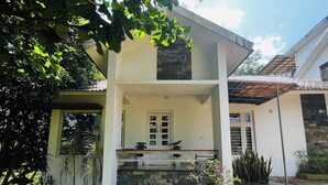 Ein zweistöckiges Haus mit Naturstein-Fassade, einem Balkon mit Blumentöpfen und einem gepflegten Garten.