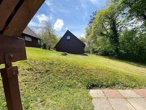 A grassy yard with a wooden structure and a building in the background.