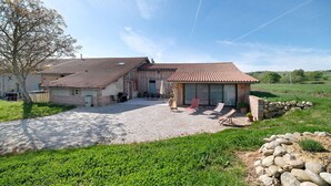 A two-story house with a gravel driveway, outdoor seating area, and a stone wall. - Gîte du petit Bigot – Tranquility and Nature at the Foot of the Pyrenees (Saverdun)