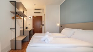 Hotellihuone, jossa on sänky, työpöytä, tuoli ja vaatekaappi.