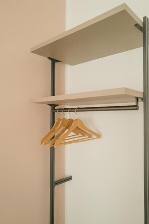 Een metalen wandrek met twee planken en een houten kapstok.