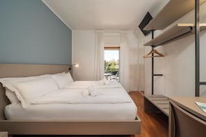 Een hotelkamer met een bed, een bureau, een televisie en uitzicht op het omliggende landschap.