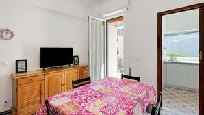 Un dormitorio con una cama, un televisor sobre un mueble de madera, un reloj en la pared y un balcón con vistas.