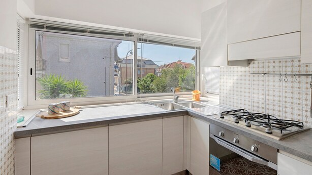 Una cocina con ventana, pileta, estufa y alacenas.