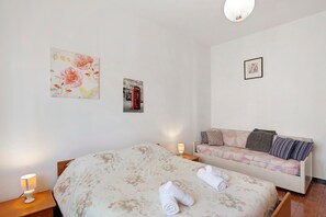Une chambre à coucher comprenant un lit, un canapé, une table de chevet et des œuvres d’art murales.