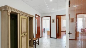 Un pasillo con un armario de madera, una silla y una puerta que da a otra habitación.