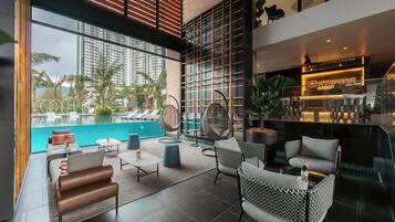 Uma área de estar moderna com vista para a piscina, com assentos confortáveis e um bar.