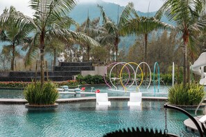 Un espace piscine aménagé avec des chaises longues, un élément décoratif aquatique et des palmiers.