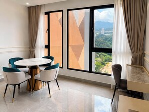 Une chambre d’hôtel équipée d’une table à manger, de chaises, offrant une vue sur le paysage urbain et dotée de grandes fenêtres avec des rideaux.