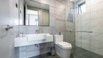 A modern bathroom with a glass shower enclosure, a white sink, and a toilet.