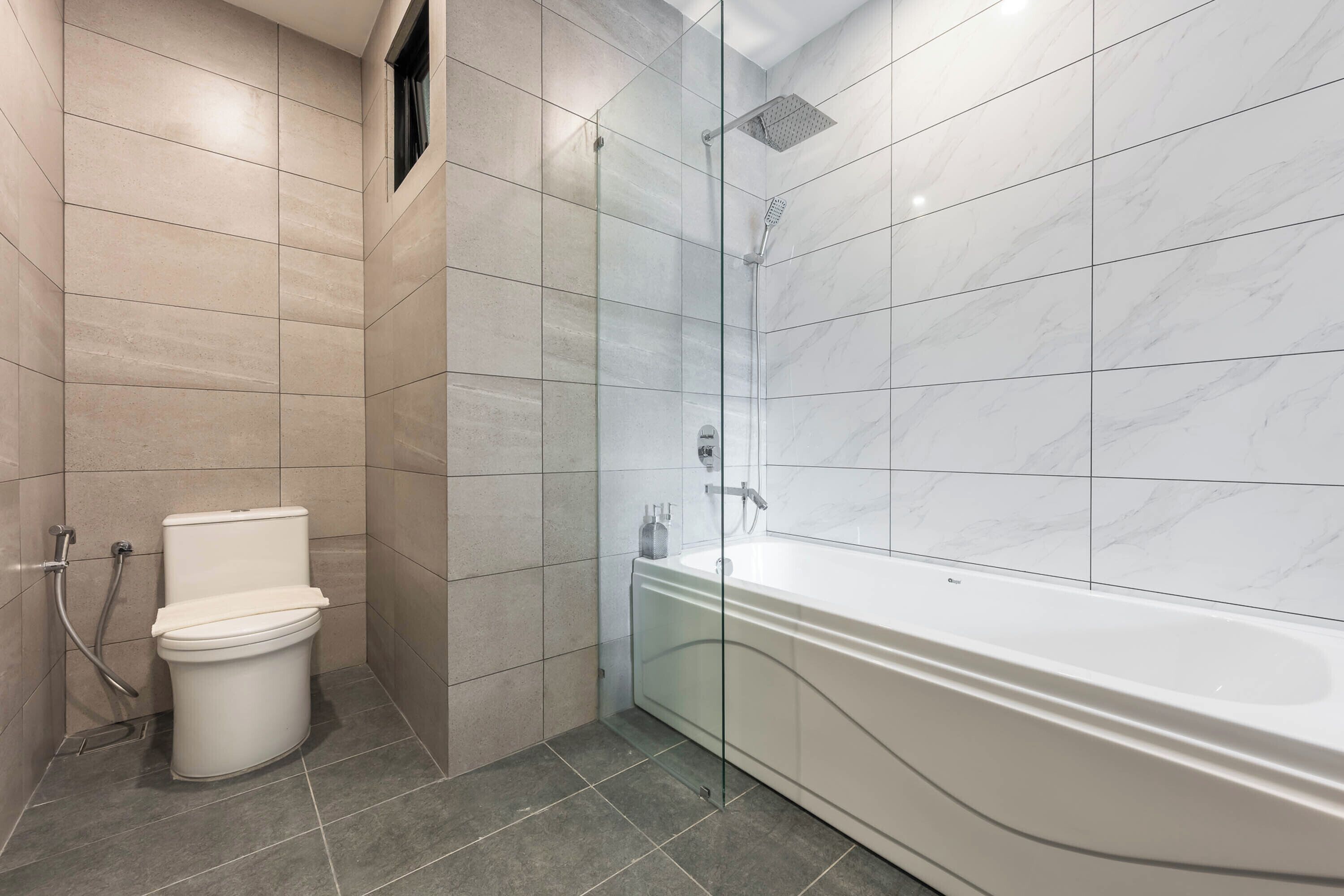 A modern bathroom with a toilet, a shower, and a bathtub.