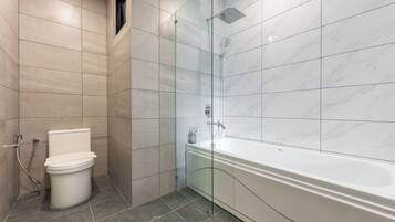 A modern bathroom with a toilet, a shower, and a bathtub.