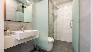 A modern bathroom with a glass shower enclosure, a white sink, and a toilet.