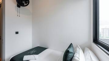 Ein Hotelzimmer mit einem Bett, einem Fenster und einem Wandventilator.