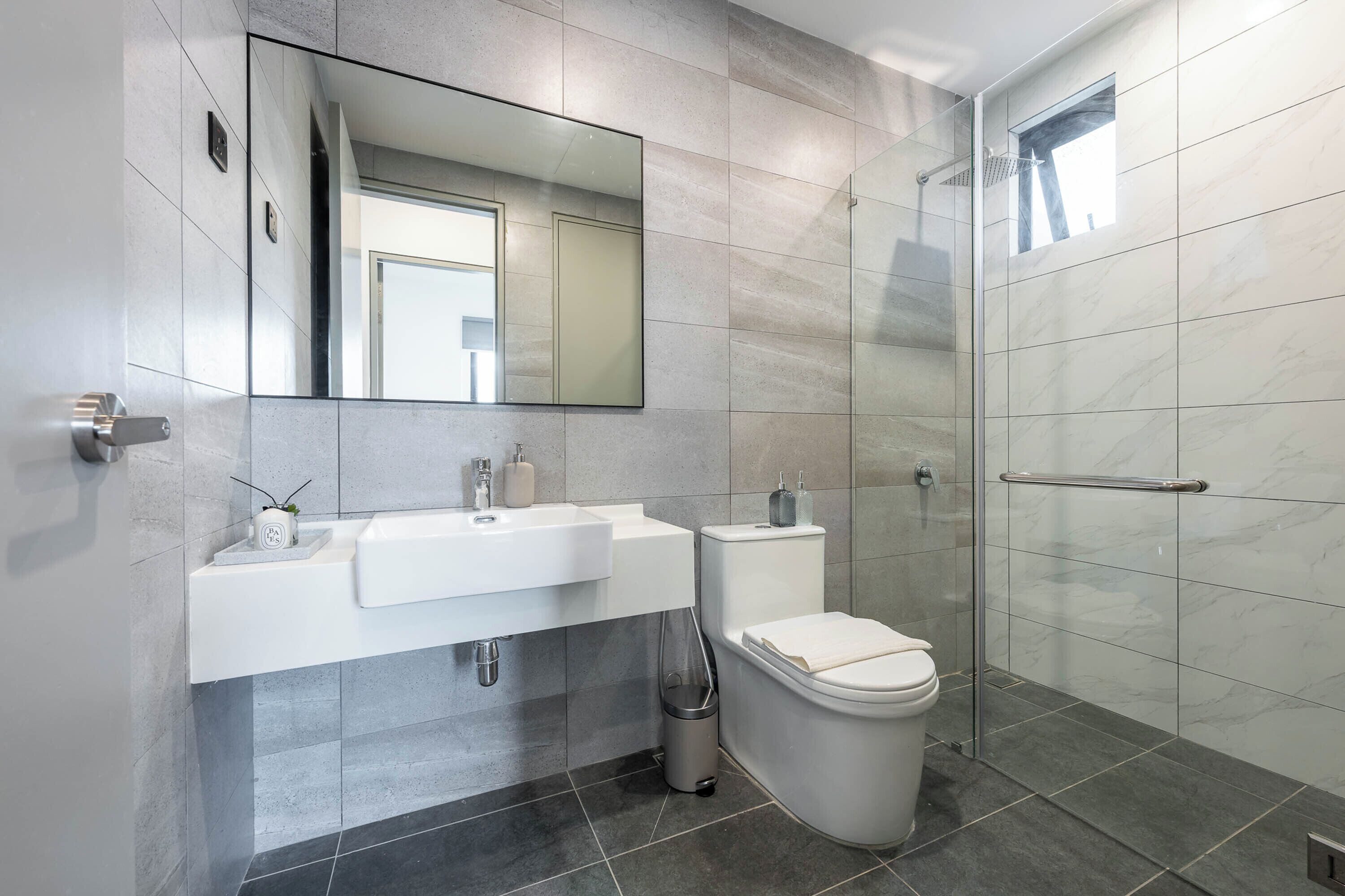 Un baño moderno con cabina de ducha de vidrio, un lavabo blanco y un inodoro.