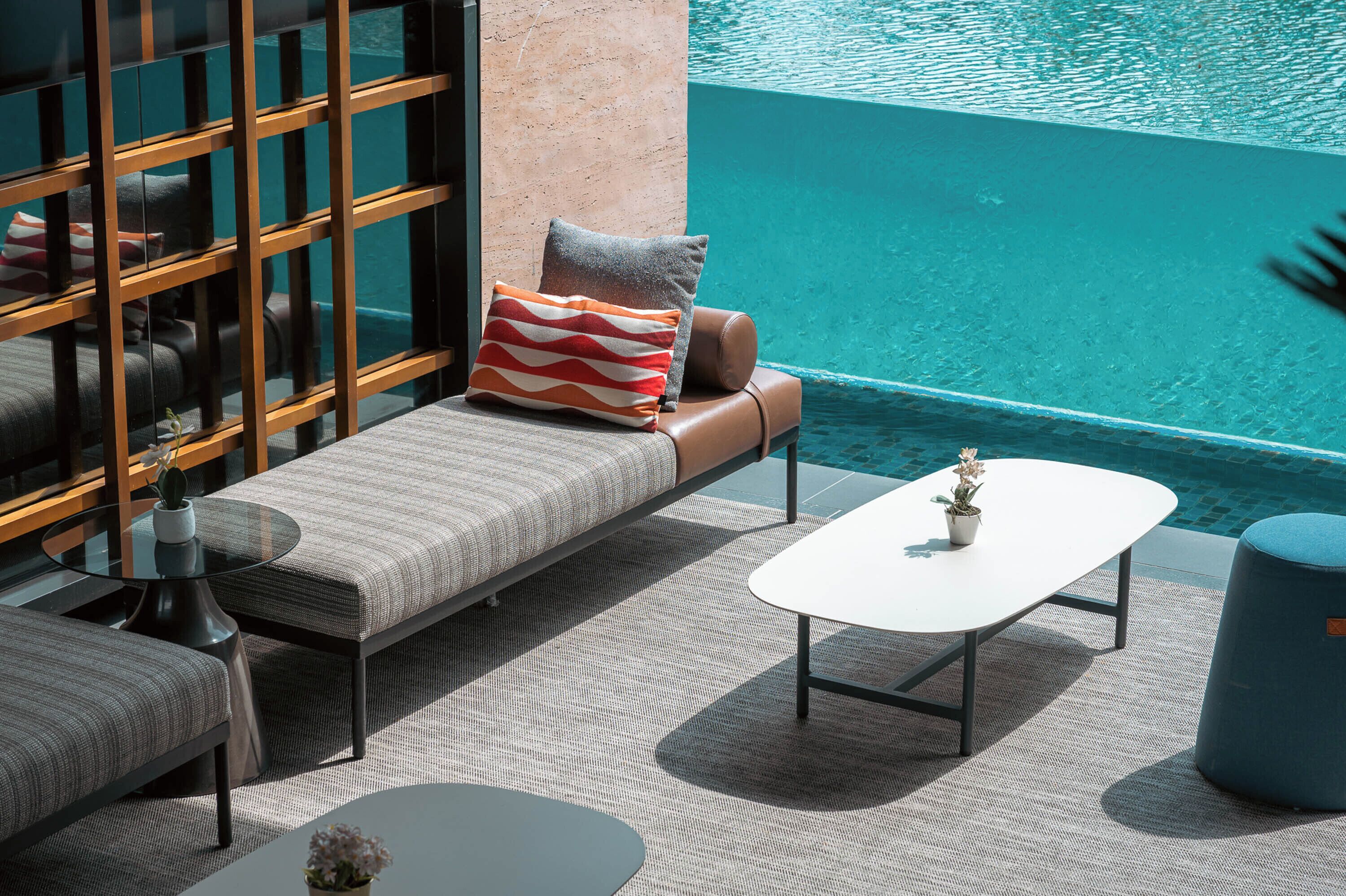 A poolside lounge area with a sofa, a round table, and a chair.