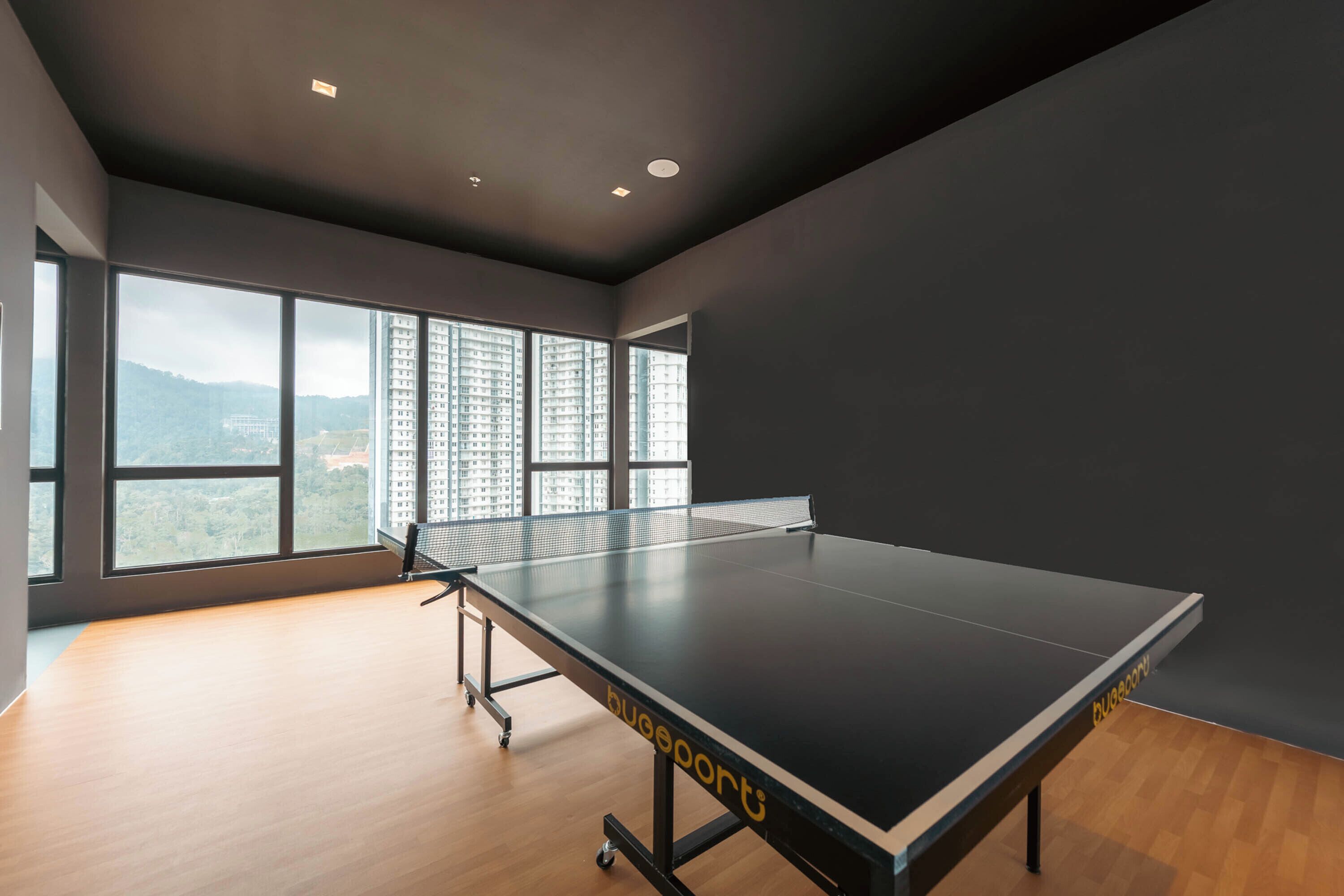 A ping pong table in a room with large windows, a view of a cityscape, and a modern interior design.