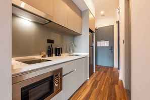 A modern kitchen with stainless steel appliances, a built-in oven, and a countertop with a sink and coffee maker. - Antharas 1 Premier Suites Genting (Genting Highlands)