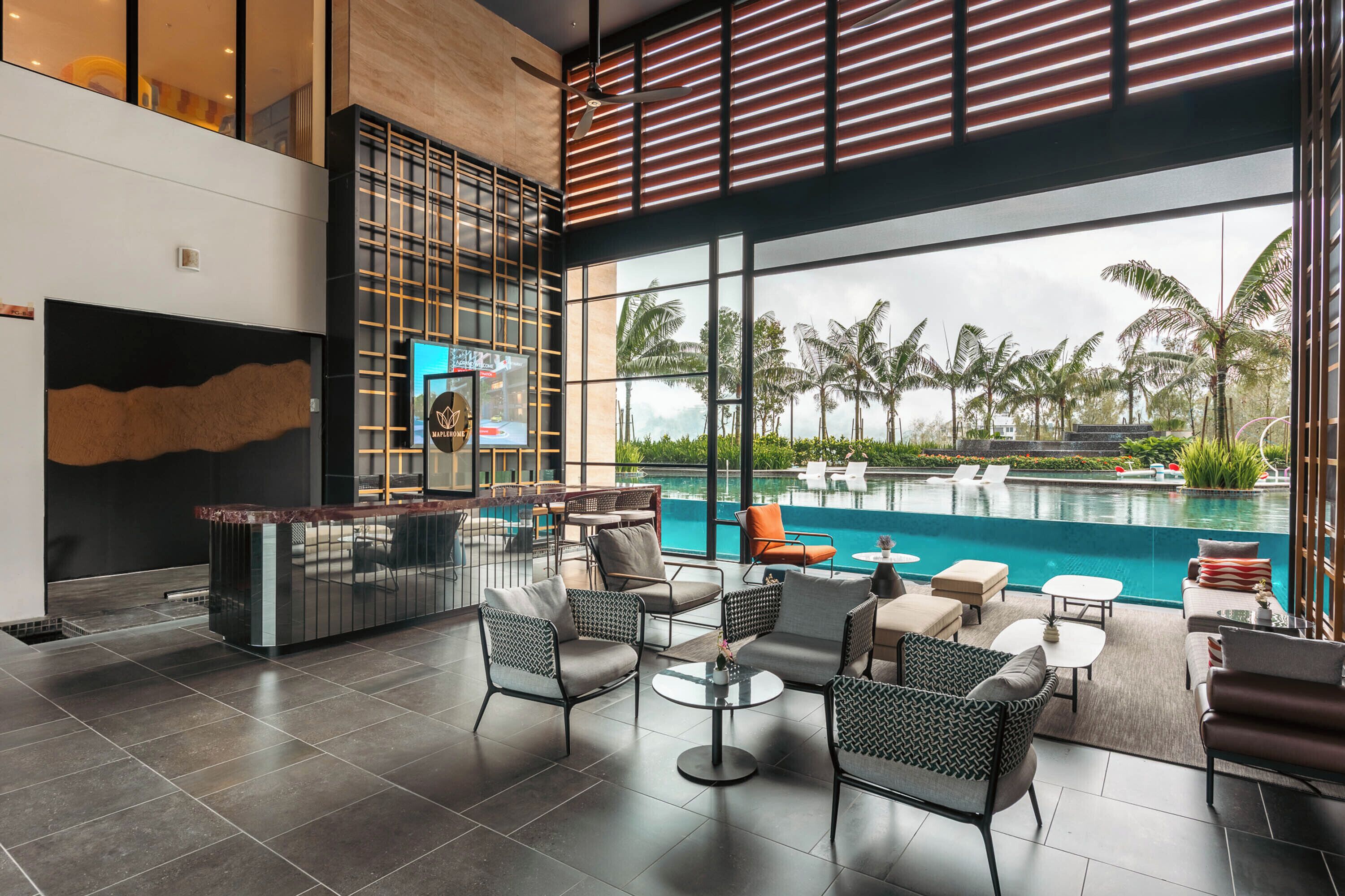 A modern hotel lobby with a reception desk, seating area, and a large window overlooking a pool.