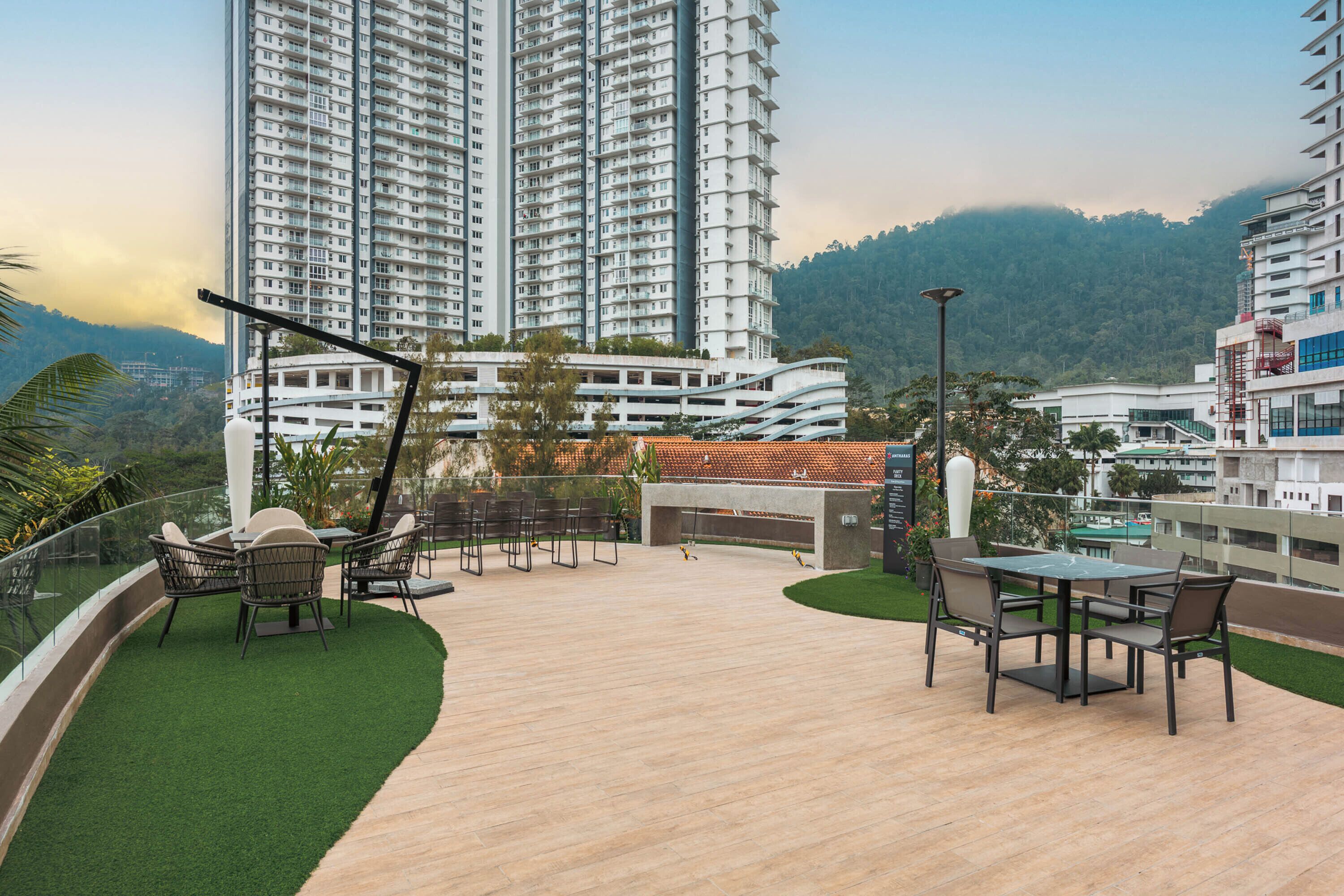 A rooftop patio with outdoor furniture, a pool, and high-rise buildings in the background.