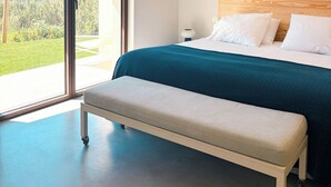 Une chambre à coucher avec un lit, un banc et une grande fenêtre.