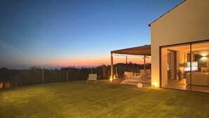 Une maison moderne avec une pelouse bien entretenue, un hamac et un espace patio.