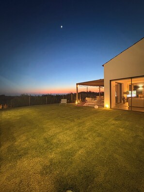 Una casa moderna con césped cuidado, una hamaca y un patio.