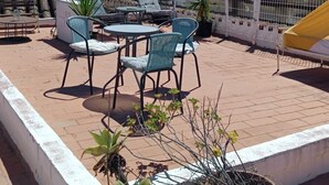 Terraza en la azotea con mobiliario exterior, plantas en macetas y vistas a edificios.