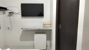 A bathroom with a toilet, a sink, a mirror, and a TV mounted on the wall. - Delta Hotel Nova Mutum (Nova Mutum)
