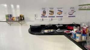 A kitchen counter with cooking utensils, a stove, and a refrigerator. There are signs on the wall indicating cooking classes. - Delta Hotel Nova Mutum (Nova Mutum)
