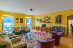 A living room with a sofa, armchairs, a TV, and a balcony with a view. - Charming 170 sqm apartment, perfect for 6 people, located on the second floor of a building with an elevator (not wheelchair accessible).The property is located in the heart of Dongo (in the restricted traffic zone), a renowned town on the western shore  (Dongo)