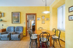 A dining area with a wooden table and chairs, a sofa, and a hanging light fixture. - Charming 170 sqm apartment, perfect for 6 people, located on the second floor of a building with an elevator (not wheelchair accessible).The property is located in the heart of Dongo (in the restricted traffic zone), a renowned town on the western shore  (Dongo)
