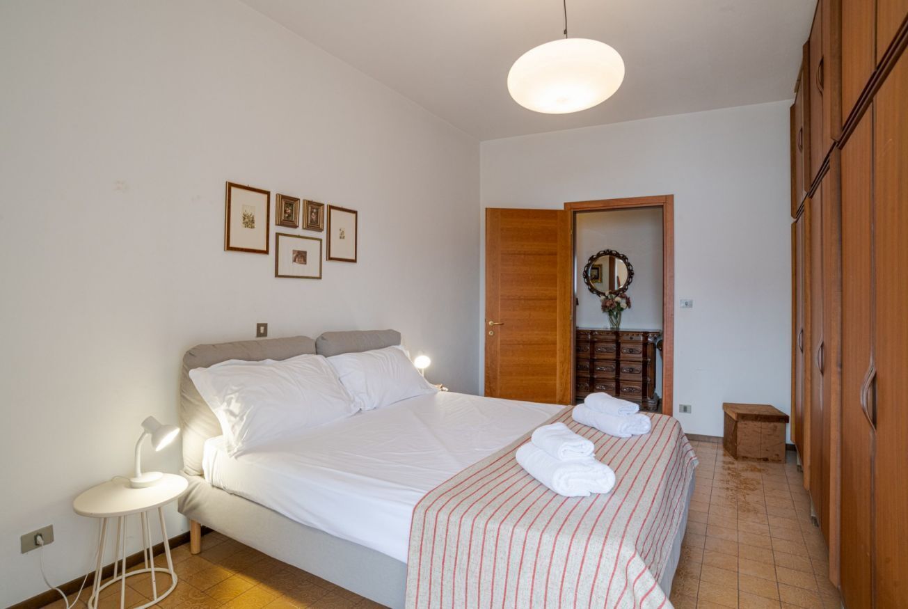 A neatly arranged bedroom with a bed, bedside lamp, and a small table.